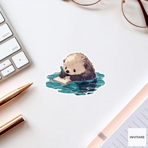 May include: A die-cut sticker featuring a cartoon sea otter with light brown fur floating in blue water. The otter is holding a small teal pencil and writing on a white spiral-bound notebook. The sticker has a white border and a glossy finish.