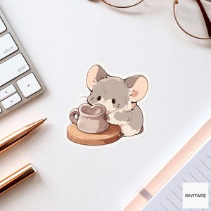 Op de afbeelding: Een sticker met een cartoon chinchilla met grijs en wit bont die een kleine, hartvormige keramische mok vasthoudt. De chinchilla staat op een ronde houten onderzetter. De illustratie maakt gebruik van zachte lijnen en gedempte kleurtinten.