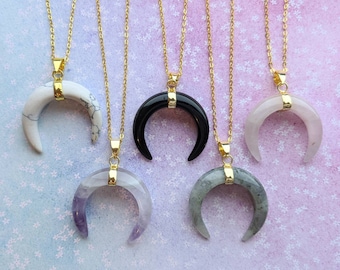 Könnte beinhalten: Fünf goldene Halsketten mit Halbmond-Anhängern aus verschiedenen Steinen. Die Steine sind weiß, schwarz, Amethyst und grau.