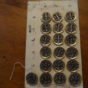 Placa de 19 bonitos botones de metal dorado de 2,2 cm de diámetro sobre cartón original de la marca Rénova, ¿antigua representación de un escudo de armas? Árbitro: K