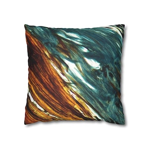 Op de afbeelding: Vierkant kussen met een abstract ontwerp. Het kussen toont een mix van turquoise, goud en witte penseelstreken, waardoor een gestructureerd, artistiek patroon ontstaat. Het ontwerp is gedrukt op het oppervlak van het kussen en biedt een decoratief element voor de interieurdecoratie.