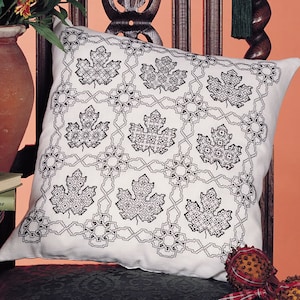 May include: A white pillow with a black embroidered design of repeating leaves in a grid pattern.