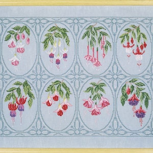 Puede incluir: Un patrón de bordado de punto de cruz con seis flores de fucsia diferentes en marcos ovalados. Las flores son de color rosa, rojo y blanco con hojas verdes. El fondo es de color azul claro.