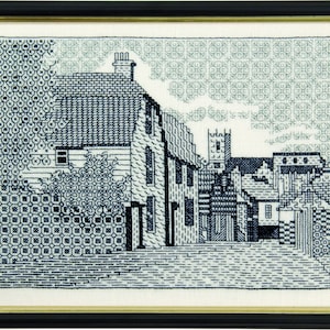 May include: Black and white cross-stitch embroidery of a small town with buildings and a church steeple.