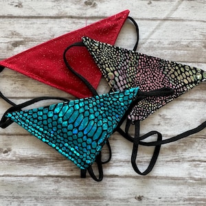 May include: Three triangle-shaped fabric pieces with black straps. One is red, one is turquoise with a scale pattern, and one is black with a pink and green scale pattern.