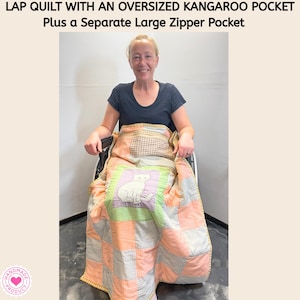 May include: A lap quilt featuring a patchwork design in shades of peach, green, and white gingham. The quilt includes an oversized kangaroo pocket and a separate large zipper pocket. A central square panel displays a white cat illustration.