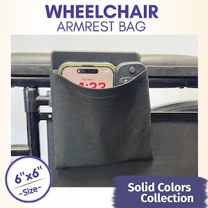 Puede incluir: Bolsa negra para reposabrazos de silla de ruedas, 15 cm x 15 cm, con un teléfono y un mando a distancia en su interior. La bolsa forma parte de la colección Colores lisos. El texto "WHEELCHAIR ARMREST BAG" está en la parte superior.