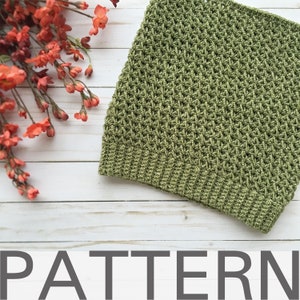 May include: A green crochet pattern for a hat or scarf. The pattern is made with a simple stitch and has a textured look.
