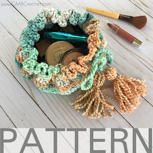 May include: A crocheted drawstring bag with a ruffled edge and two tassels. The bag is filled with makeup and brushes, including a Rimmel Stay Matte foundation.