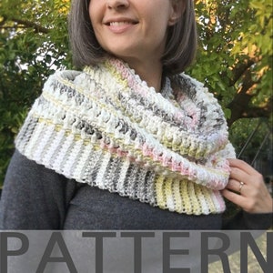 May include: A crocheted cowl in shades of white, gray, yellow, and pink. The cowl is worn by a person standing in front of a tree with yellow leaves. The text "PATTERN" is at the bottom of the image.