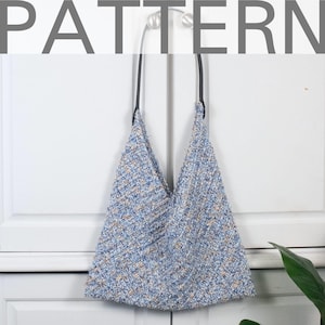 Op de afbeelding: Een blauwe en witte gepatroneerde tote bag met zwarte leren hengsels. De tas hangt aan een witte kastdeur.