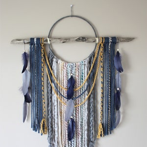 May include: A macrame wall hanging with a wooden branch, a metal ring, and blue and yellow yarn. The hanging features several blue feathers.