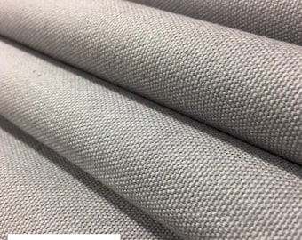 May include: Close-up of a light gray canvas fabric with a textured weave. The fabric is folded in half, showing the underside of the material.