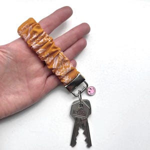 Llavero elástico para sujetar a tu muñeca. Especie de coletero para muñeca; Ideal para sujetar tus llaves. De color óxido
