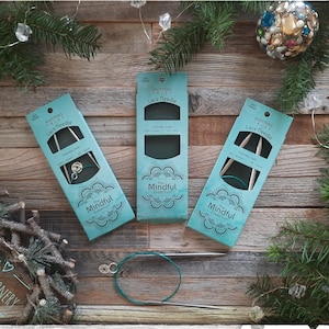 May include: Three packages of knitting needles in a teal and green color scheme with the text "Knitters Pride Lace Needle" and "The Mindful Collection".