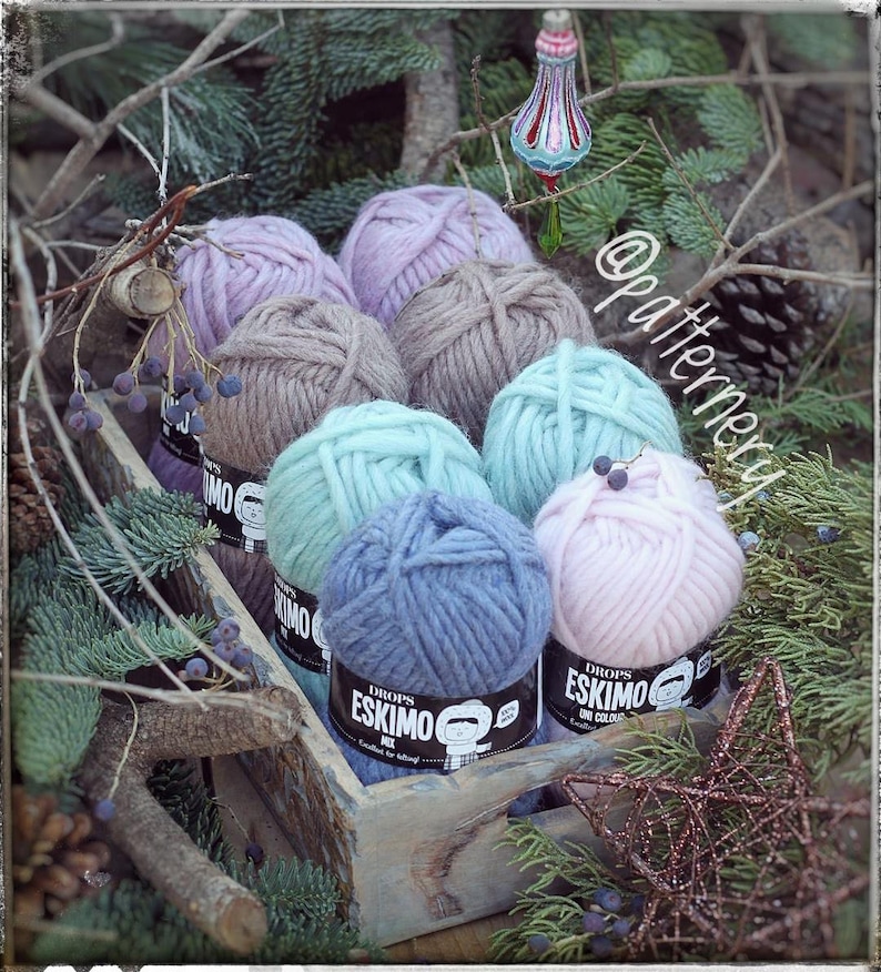 May include: A wooden box filled with eight balls of yarn in various colours, including pink, blue, green, and brown. The yarn is labelled "DROPS ESKIMO" and "DROPS ESKIMO ONE COLOUR".