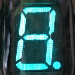 Może przedstawiać: Zielona lampa Nixie wyświetlająca cyfrę "8" z podświetlanym, segmentowym wyświetlaczem.