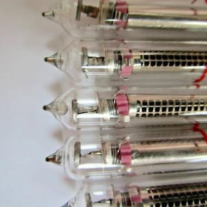 May include: Five clear glass tubes with silver metal components and a pink and black grid pattern. The tubes are arranged vertically, with the top tube slightly offset to the right.