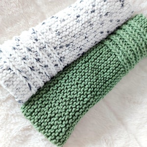 Peut inclure: Deux torchons en tricot, un blanc avec des points gris et un vert uni.