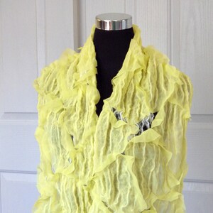 May include: A bright yellow ruffled scarf made of wool. The scarf is draped over a mannequin's shoulders. The text "Galina Shawls" is visible at the bottom of the image.