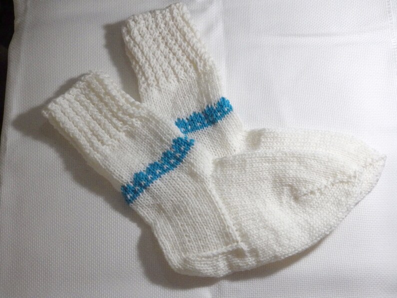 K&ouml;nnte beinhalten: Ein Paar wei&szlig;e Stricksocken mit einem blauen Streifen &uuml;ber dem Schaft jeder Socke.