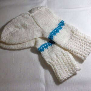 K&ouml;nnte beinhalten: Ein Paar wei&szlig;e Stricksocken mit einem blauen Musterband um den oberen Teil jeder Socke.