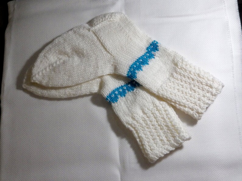 K&ouml;nnte beinhalten: Ein Paar wei&szlig;e Stricksocken mit einem blauen Musterband um den oberen Teil jeder Socke.