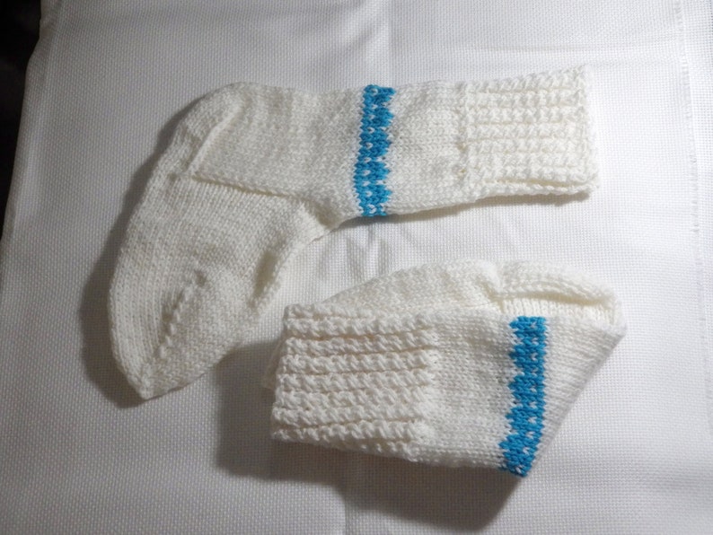 K&ouml;nnte beinhalten: Ein Paar wei&szlig;e Stricksocken mit einem blauen Streifen am oberen Rand jeder Socke.