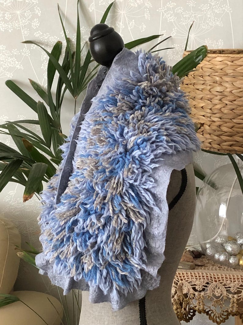 Pode incluir: Uma echarpe de l&atilde; azul claro com um design felpudo e texturizado. A echarpe &eacute; feita de um material macio e confort&aacute;vel e tem uma borda franjada.