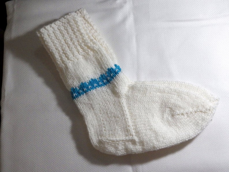 K&ouml;nnte beinhalten: Wei&szlig;e Stricksocke mit einem blauen Streifen um den Kn&ouml;chel.