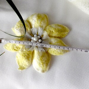 以下が含まれることがあります： パールとビーズのセンターが付いた黄色と白のフェルトの花のブローチ。メジャーで測定すると、幅は約10インチです。