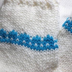 K&ouml;nnte beinhalten: Wei&szlig;e Stricksocken mit einem blauen Streifen. Die Socken sind aus einem weichen, bequemen Material gefertigt und haben ein schlichtes Design.