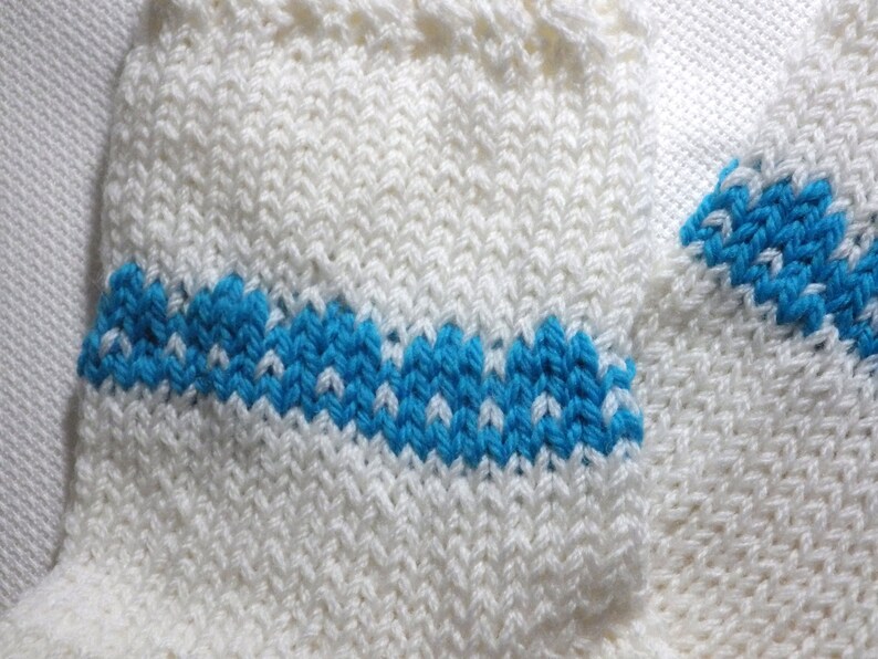 K&ouml;nnte beinhalten: Wei&szlig;e Stricksocken mit einem blauen Streifen. Die Socken sind aus einem weichen, bequemen Material gefertigt und haben ein schlichtes Design.