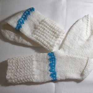 K&ouml;nnte beinhalten: Zwei wei&szlig;e Stricksocken mit blauen Streifen. Eine Socke ist umgeklappt und die andere liegt flach.