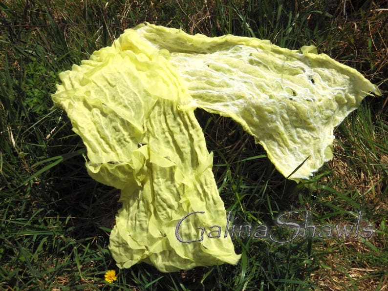 May include: A yellow silk scarf with a crinkled texture. The scarf is draped over green grass.
