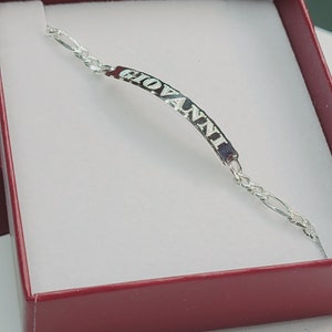 May include: A silver bracelet with a nameplate that reads "GIOVANNI". The bracelet is in a red box.