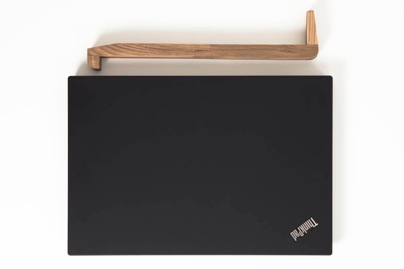 May include: A black laptop computer with the ThinkPad logo on the bottom right corner. A wooden laptop stand is positioned above the laptop.