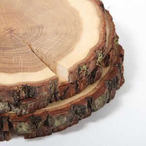 Puede incluir: Tres rebanadas de madera apiladas con corteza, mostrando la veta natural y los anillos de la madera. La rebanada superior es la m&aacute;s grande y tiene una grieta natural en el centro.