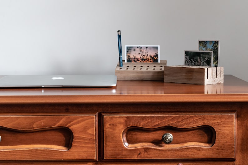 May include: A wooden desk organizer with a pen holder and slots for photos. The organizer is on a wooden desk with two drawers. A laptop is on the desk.