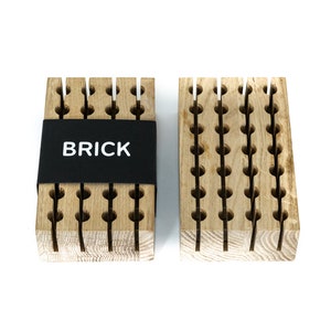 May include: Two wooden blocks with a grid pattern and holes. The block on the left has a black label that says "BRICK".
