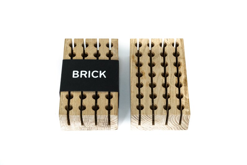 May include: Two wooden blocks with a grid pattern and holes. The block on the left has a black label that says "BRICK".