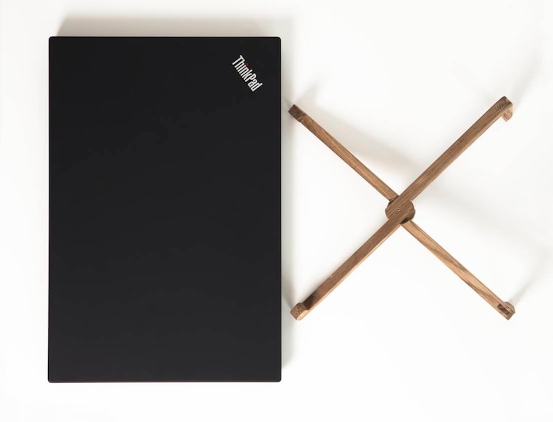 May include: A black laptop computer with the ThinkPad logo on the lid, next to a wooden laptop stand.