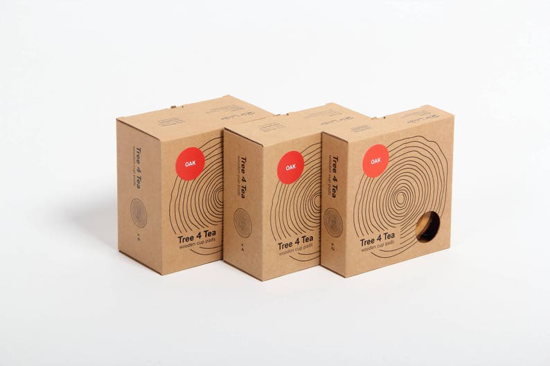 Puede incluir: Tres cajas de cart&oacute;n marr&oacute;n con el texto "Tree 4 Tea" y "OAK" impreso en ellas. Las cajas est&aacute;n apiladas una encima de la otra y tienen un patr&oacute;n de veta de madera.