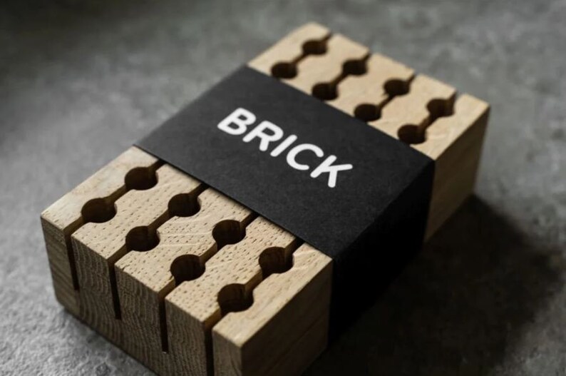 May include: A wooden organiser with a black label that says "BRICK". The organiser has multiple slots for storing items like pens, pencils, or other small objects.