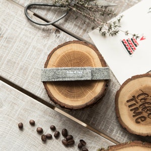 Puede incluir: Conjunto de cuatro posavasos de madera con una banda de fieltro gris. Los posavasos est&aacute;n hechos de corteza de &aacute;rbol y tienen un acabado de madera natural. Un posavasos tiene el texto "Coffee Time" grabado en &eacute;l. Otro posavasos tiene el texto "Tree 4 Tea" grabado en &eacute;l.