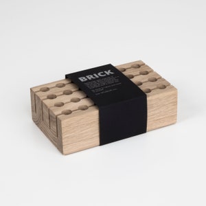 May include: A wooden organiser with a black label that reads "BRICK Handmade with the impulse of nature, each piece is naturally unique.  Be connected to nature and close to yourself. Size 147x72x48 mm."
