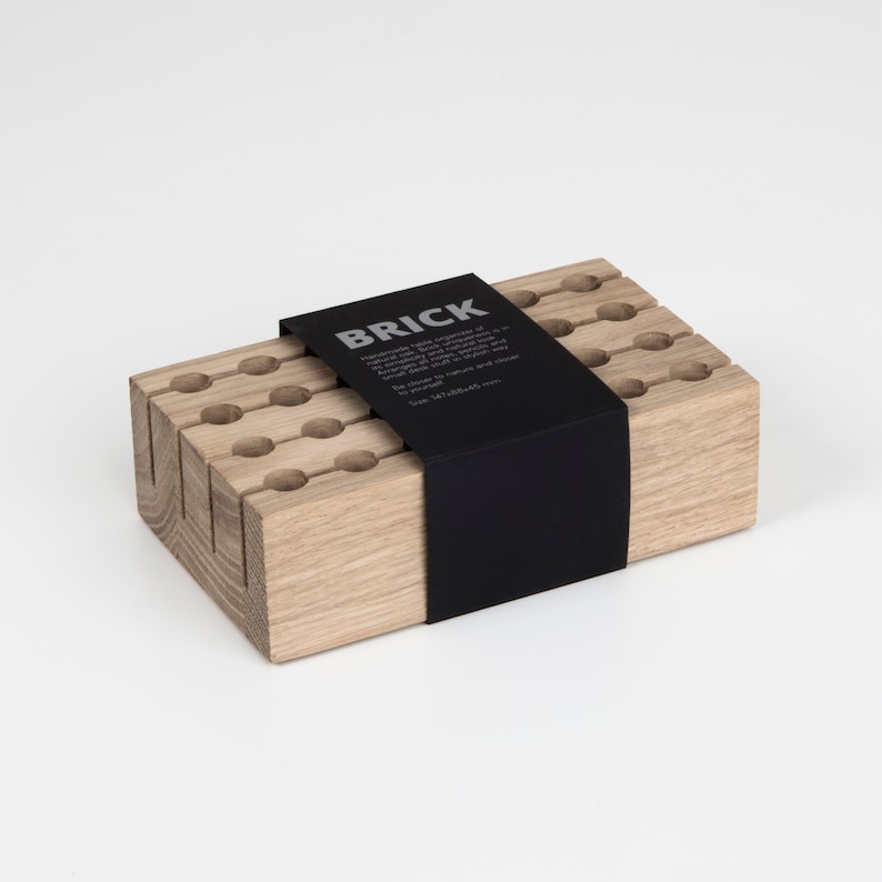 May include: A wooden organiser with a black label that reads "BRICK Handmade with the impulse of nature, each piece is naturally unique.  Be connected to nature and close to yourself. Size 147x72x48 mm."