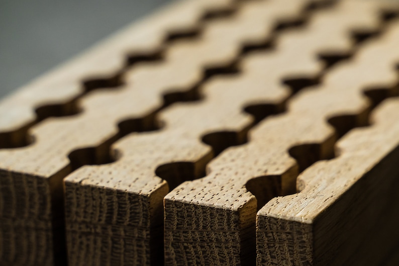 May include: Close-up of a wooden board with a repeating pattern of interlocking grooves. The board is light brown in colour and has a natural wood grain.