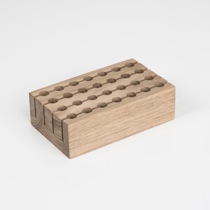 May include: A wooden organiser with multiple rows of round holes, ideal for storing small items such as pens, pencils, or makeup brushes.