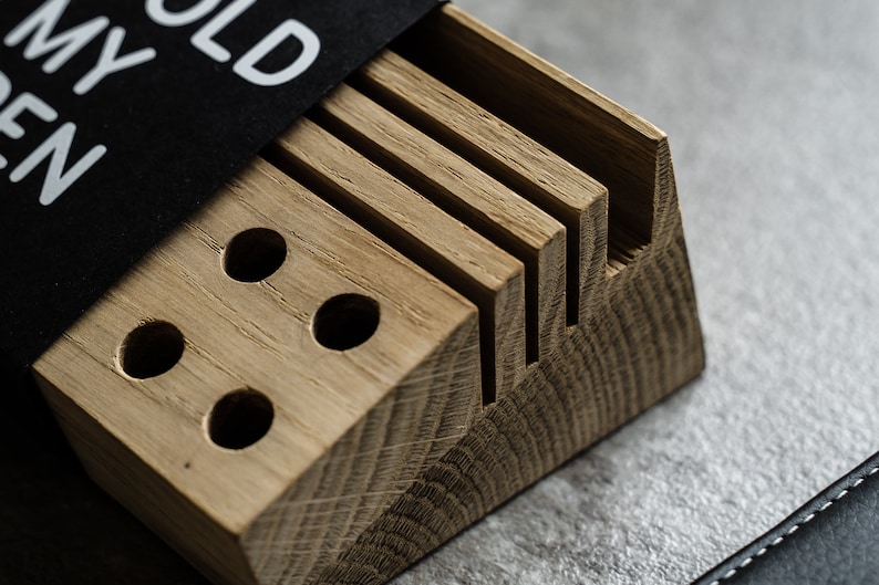 May include: A wooden organizer with slots for holding knives and a section with three round holes. The organizer is made of light brown wood and has a natural finish. The text "HOLD MY KNIVES" is printed on a black label attached to the organizer.